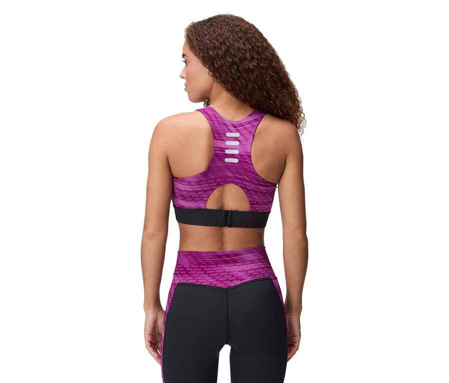 Vue arrière d'une femme aux cheveux bouclés portant un soutien-gorge de sport et un legging violet et noir.