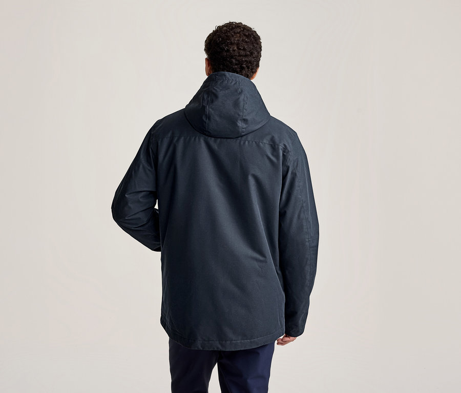 Homme vu de dos portant une veste à capuche bleu foncé et un pantalon foncé.