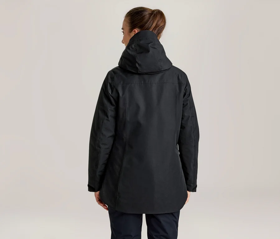 Femme de dos portant une veste noire à capuche et un pantalon foncé, les cheveux attachés.