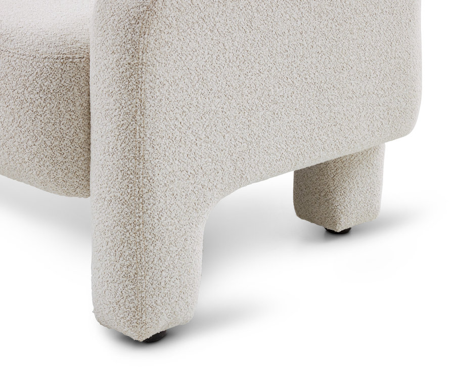 Partie inférieure d'un fauteuil ou d'un canapé texturé de couleur crème, montrant deux pieds courts et épais avec des patins noirs sur un fond blanc.
