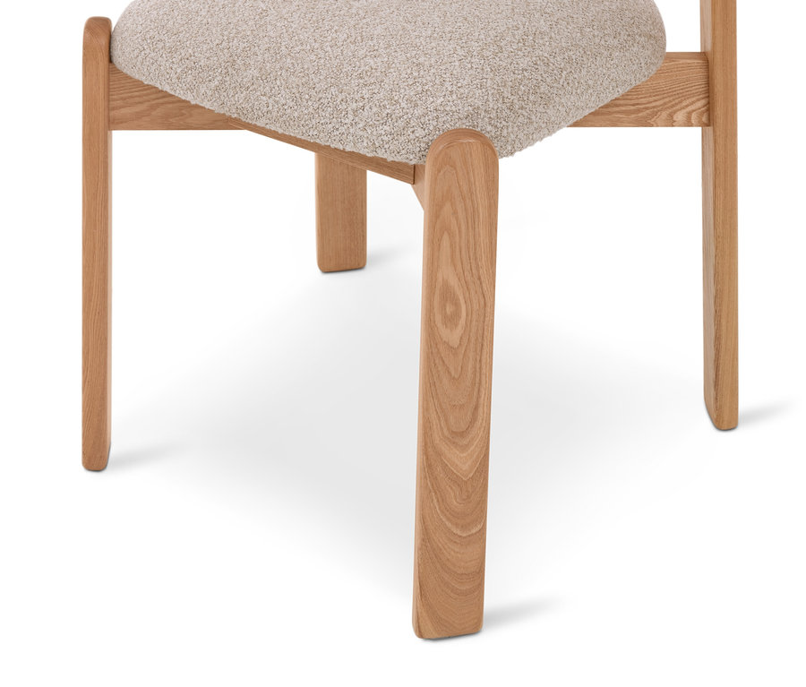 Partie inférieure d'une chaise avec des pieds en bois clair et une assise rembourrée claire et texturée.