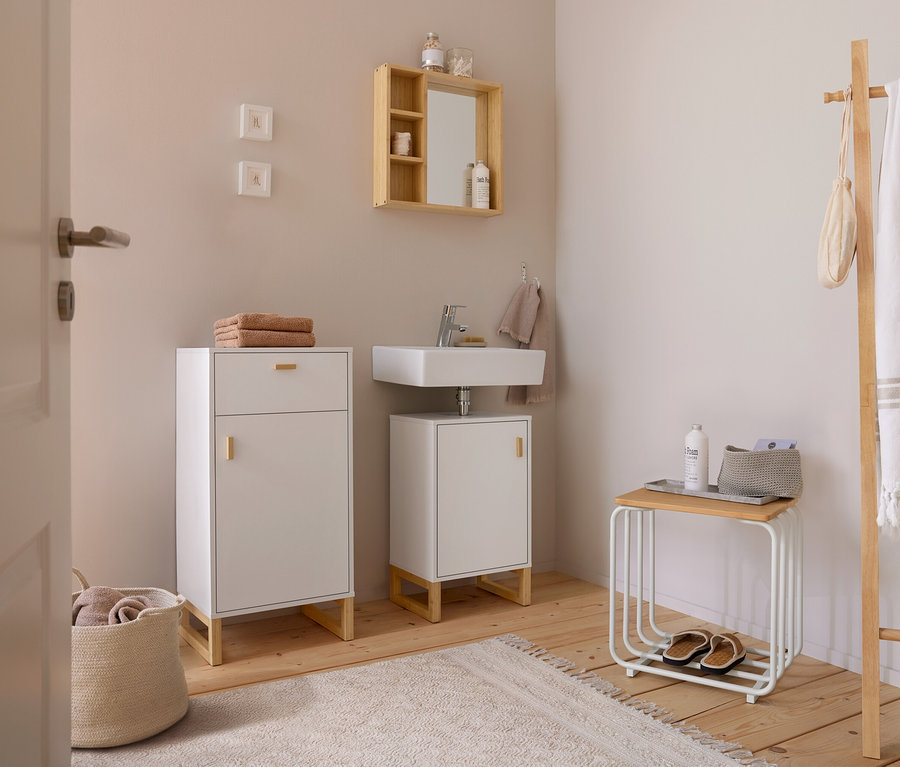 Salle de bain lumineuse avec miroir à étagères, meuble sous-vasque blanc avec porte, meuble d'appoint avec porte et tiroir, table d'appoint et porte-serviettes.