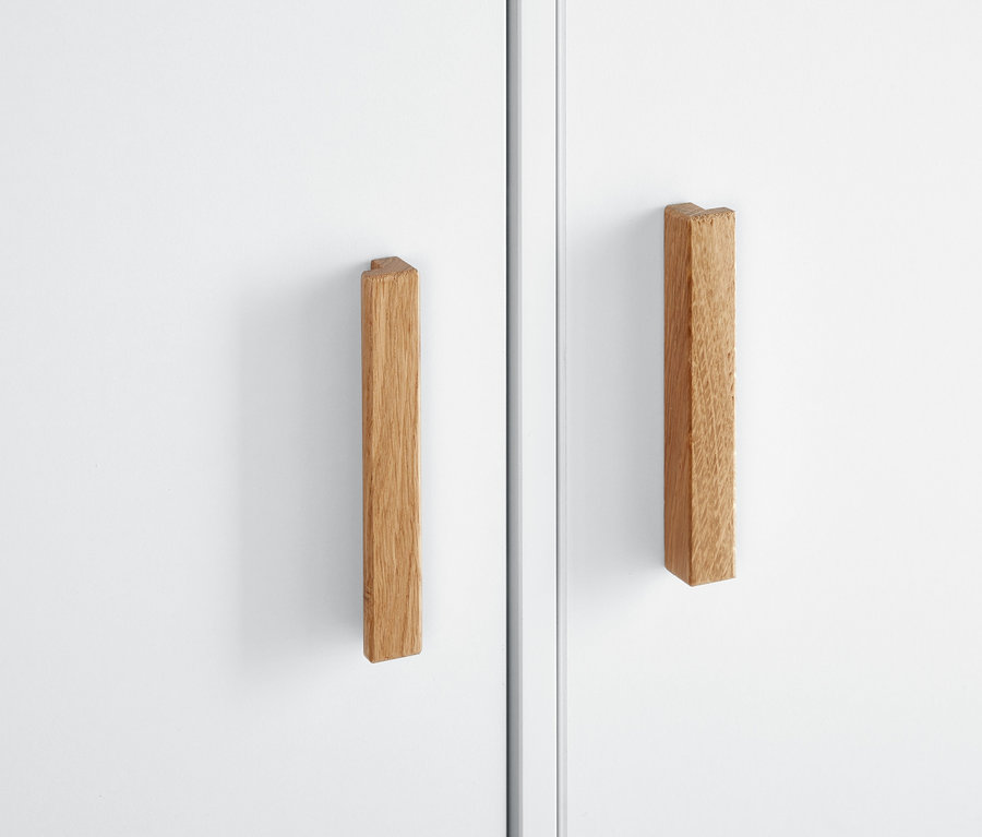 Gros plan sur une armoire blanche avec des poignées en bois.