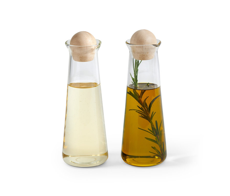 Deux bouteilles pour huile et vinaigre avec bouchons en bois. L'une avec un liquide clair, l'autre avec de l'huile d'olive et du romarin.