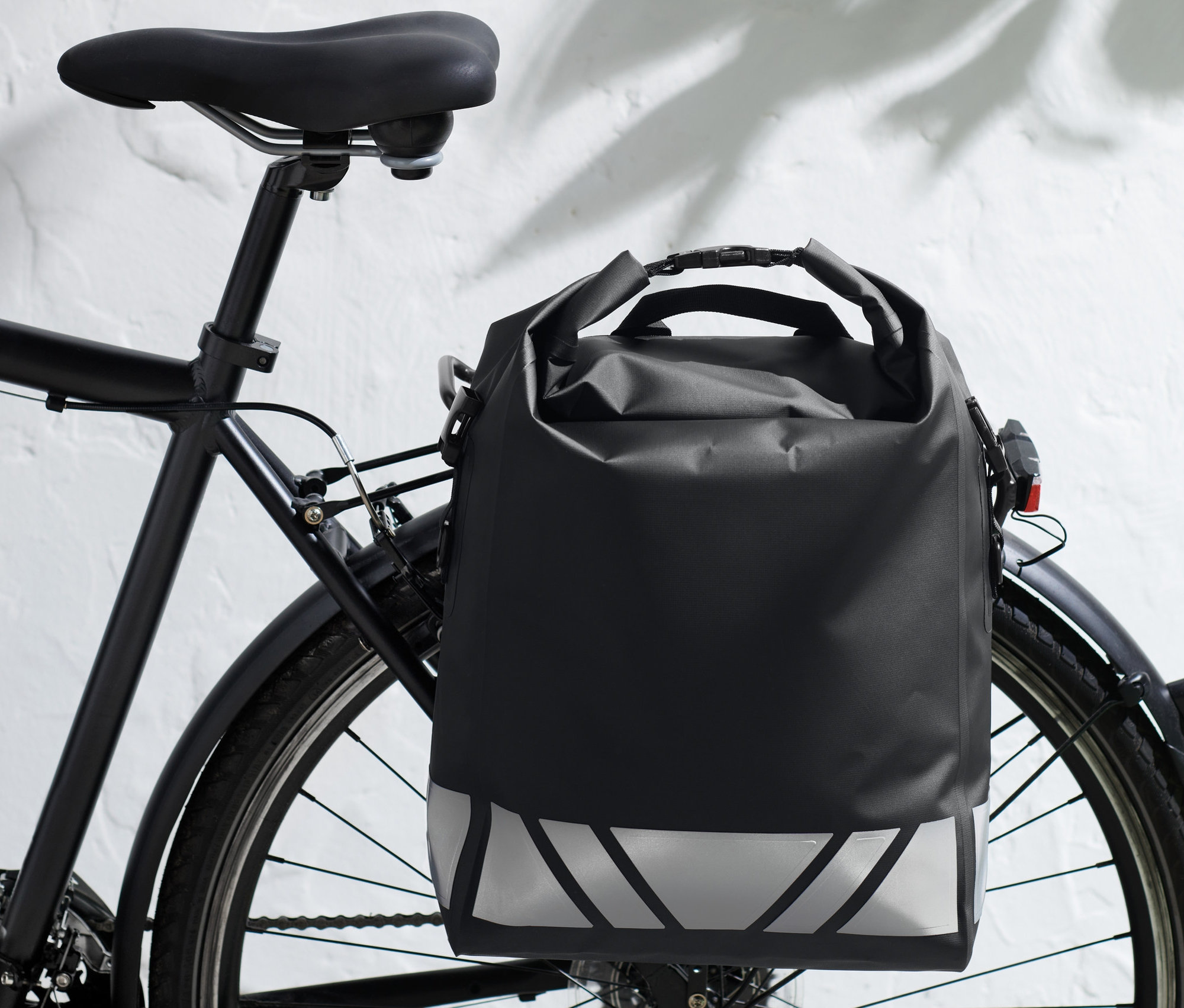 Une sacoche imperméable noire pour vélo est fixée au porte-bagages arrière d'un vélo.