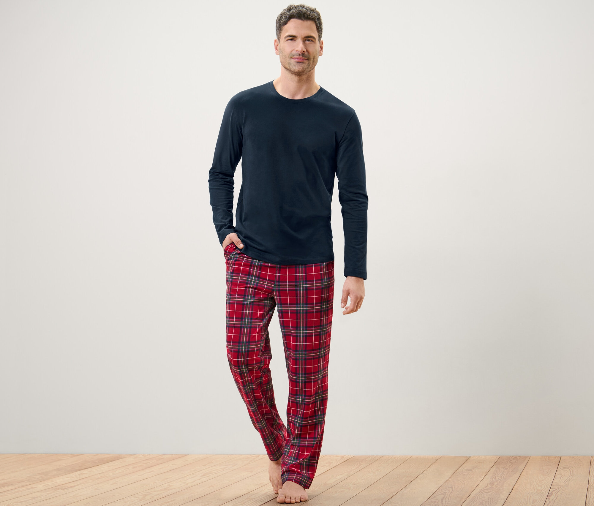 Un homme pose en pyjama bleu avec un pantalon à carreaux.