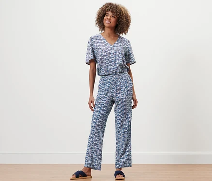 Femme posant en pantalon et haut à imprimé intégral.