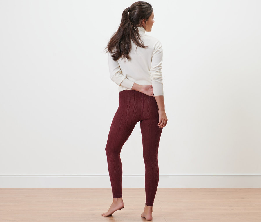 Une femme pose, dos à la caméra, portant des leggings thermiques à motif torsadé et un haut blanc.
