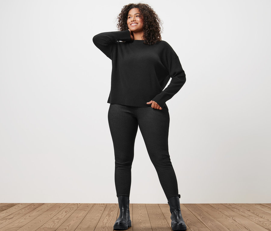 Femme posant en pull en maille fine avec du cachemire et legging doublé à l’aspect jean.