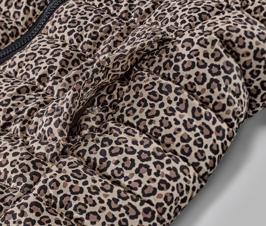 Détail d'un gilet sans manche matelassé imprimé à capuche avec fermeture à bouton-pression.