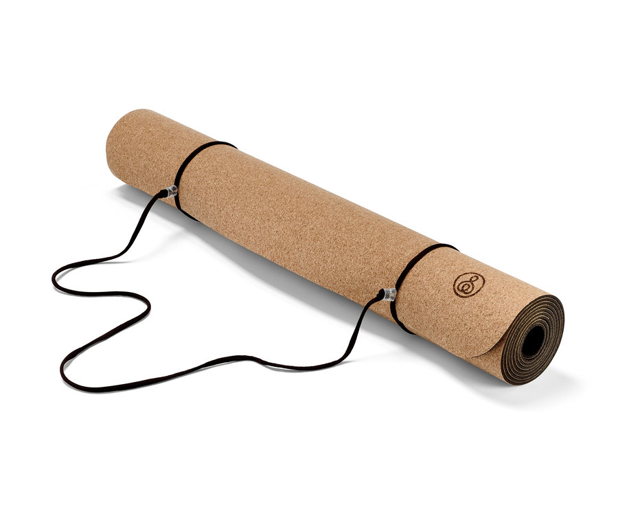 Un tapis de yoga et de fitness en liège enroulé avec des sangles noires.