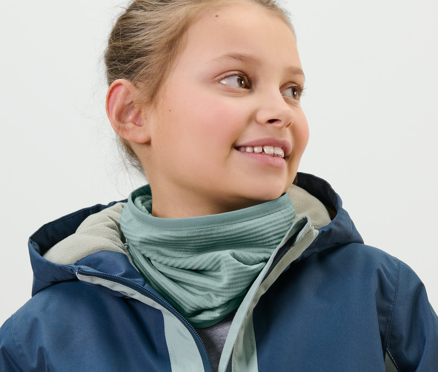 Fillette portant un foulard multifonction pour enfant et une veste bleue.