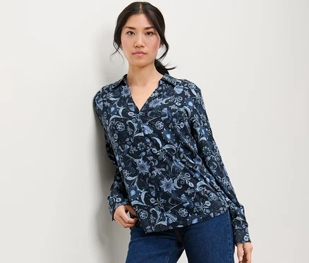 Femme posant en chemisier imprimé avec patte de boutonnage et jean.