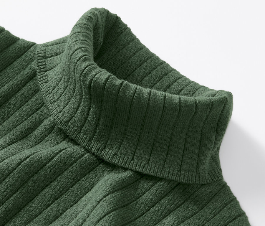 Gros plan d'un pull à col roulé côtelé vert.
