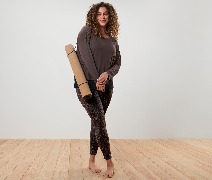 Femme posant avec un t-shirt de sport 2 en 1 marron et un legging de sport réversible noir et marron.