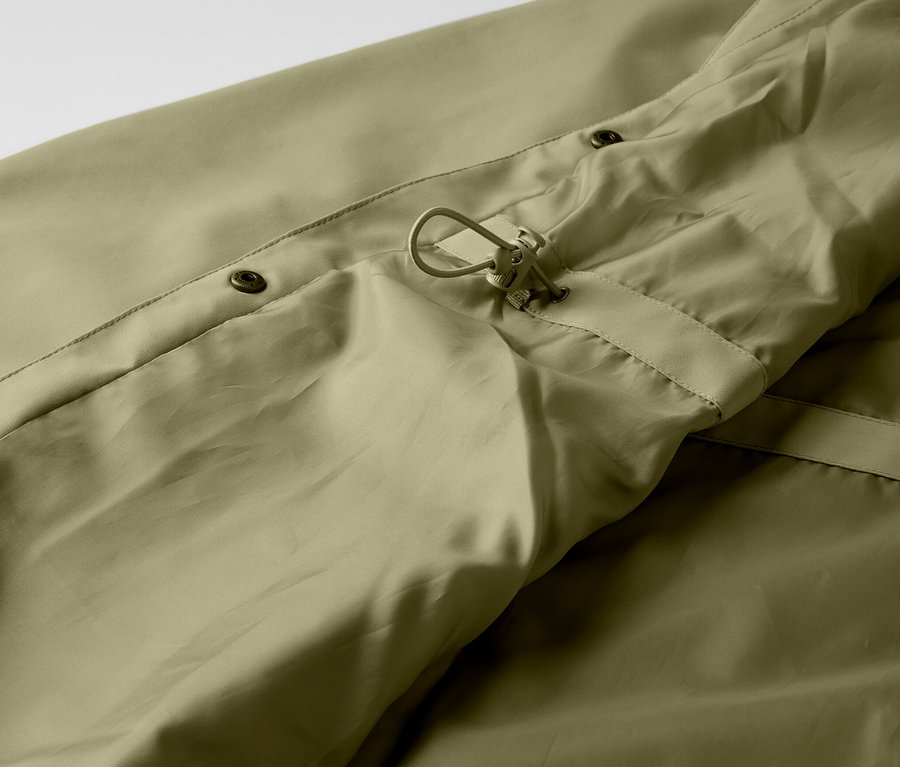 Gros plan sur un manteau de pluie kaki avec boutons et cordon de serrage.