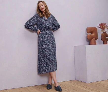 Femme posant en robe midi à imprimé floral.