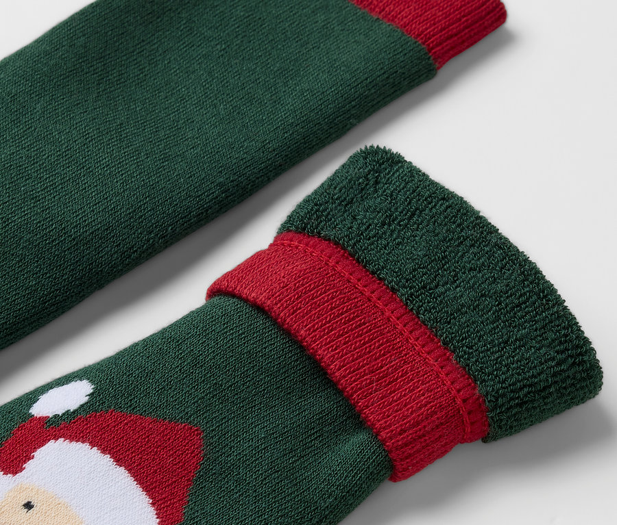 Gros plan d'une chaussette verte avec un bord rouge et un motif de Père Noël.