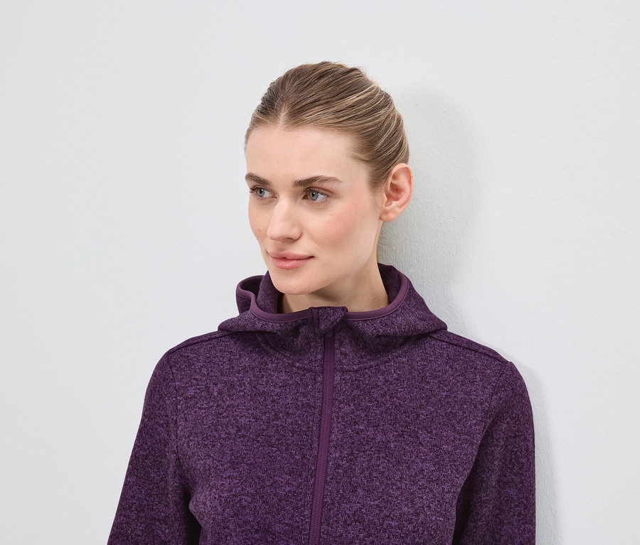 Portrait d'une femme blonde portant un sweat à capuche violet.