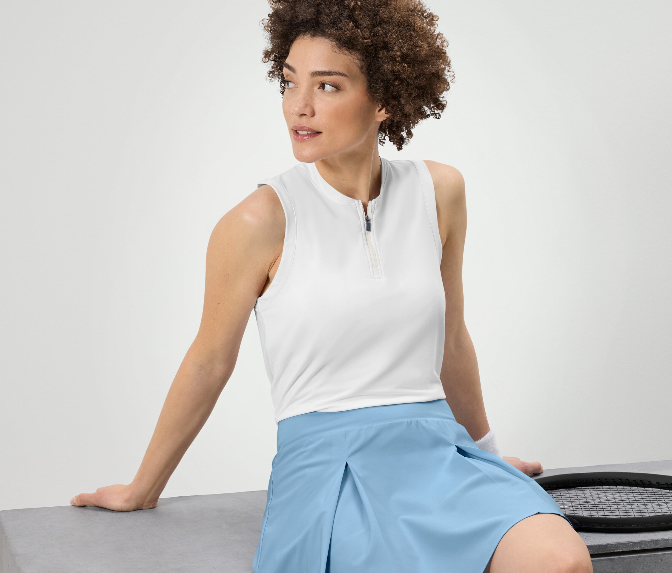 Femme assise portant un top fonctionnel blanc.