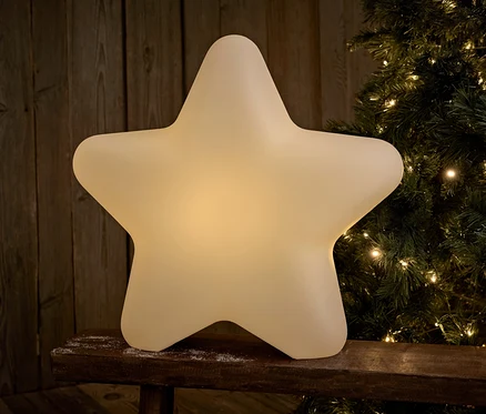 Décoration lumineuse en forme d'étoile sur un banc en bois devant un sapin de Noël.