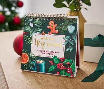 Calendrier de table avec un motif de Noël et une boîte cadeau avec un ruban vert sur une table.