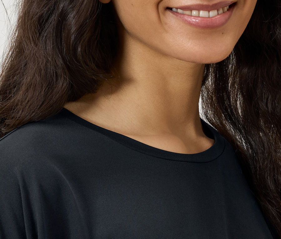 Gros plan sur le visage d'une femme aux cheveux bruns ondulés portant un t-shirt noir.