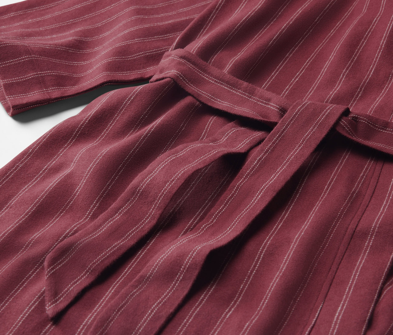 Gros plan d'une robe de chambre rayée bordeaux avec une ceinture nouée.