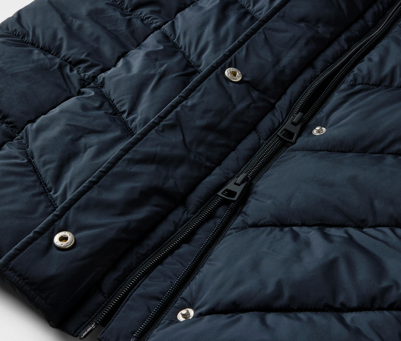 Vue détaillée d'un manteau matelassé bleu foncé avec capuche.