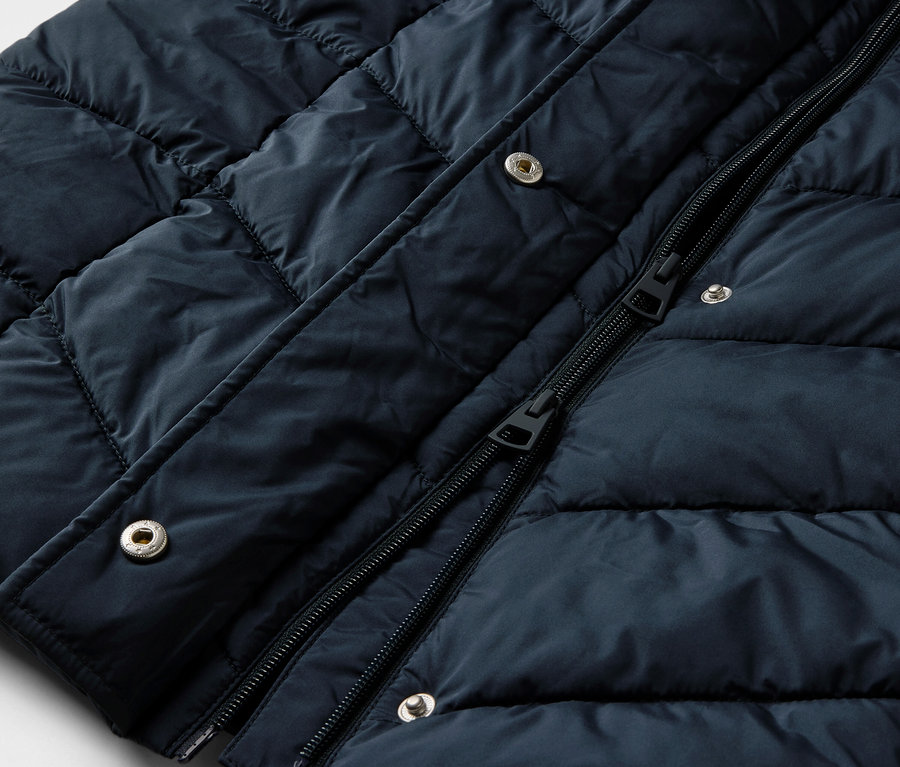 Vue détaillée d'un manteau matelassé bleu foncé avec capuche.