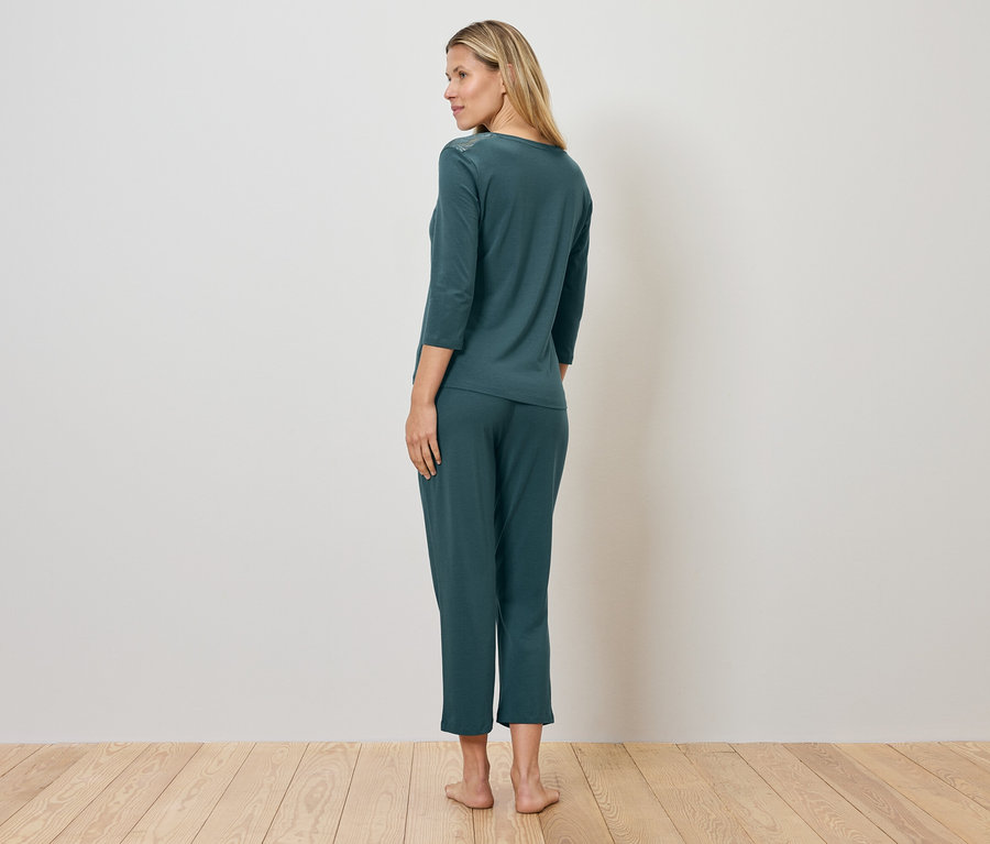 Femme en pyjama vert debout sur un plancher en bois.