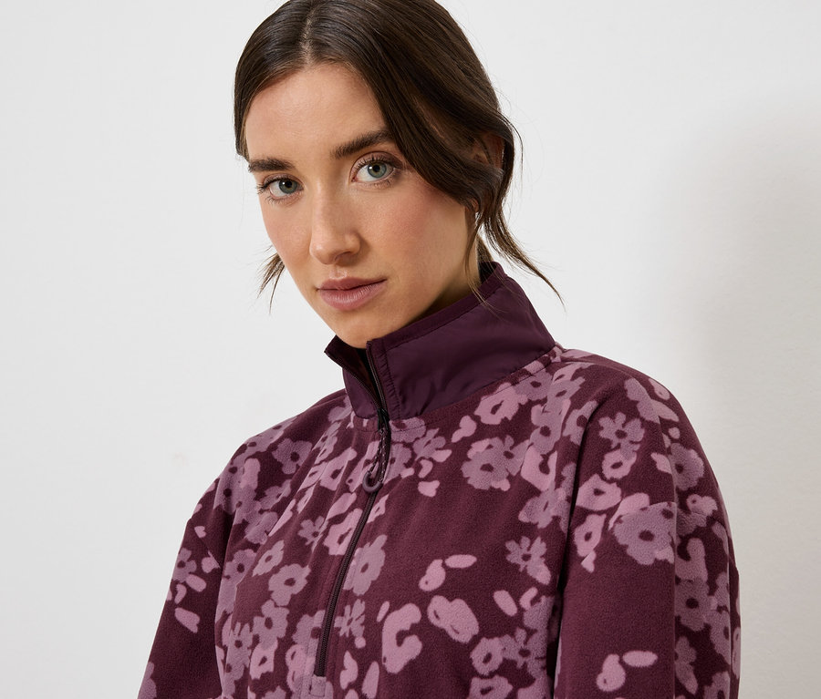 Portrait d'une femme portant une veste bordeaux à motif floral.