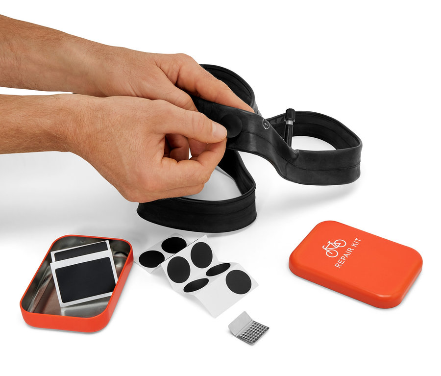 Un homme répare une chambre à air de vélo avec un kit de réparation vélo.