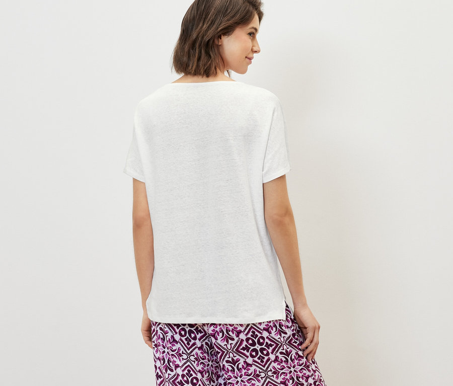 Femme vue de dos portant un t-shirt blanc en lin mélangé et un pantalon à motifs.