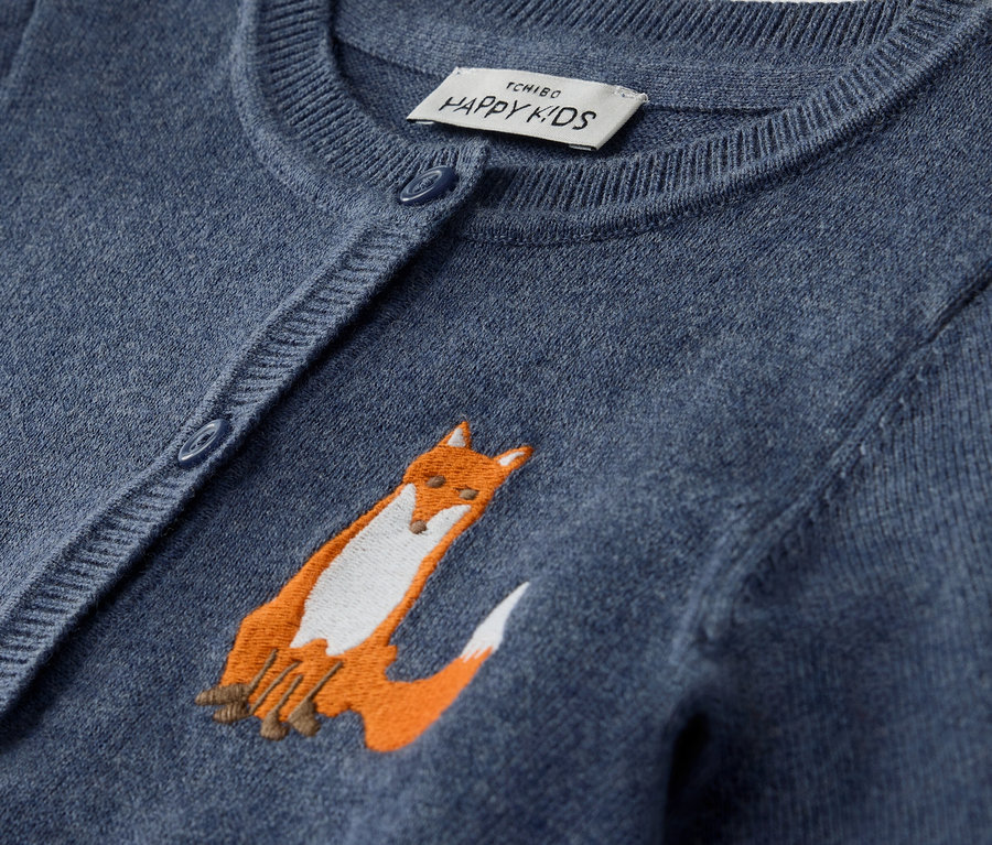 Gros plan sur une veste en maille pour bébé bleue avec une broderie de renard.