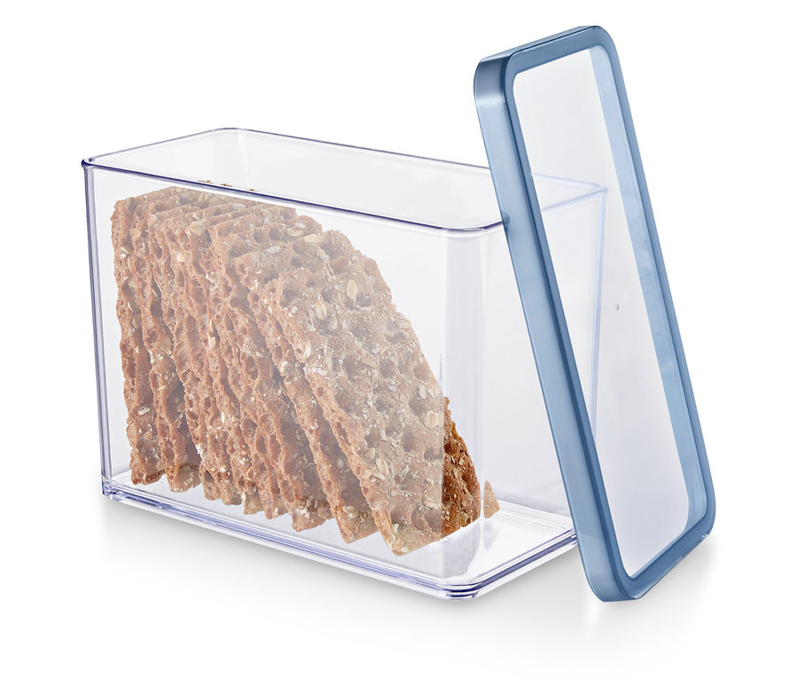 Un récipient transparent avec un bord bleu rempli de crackers de grains entiers.
