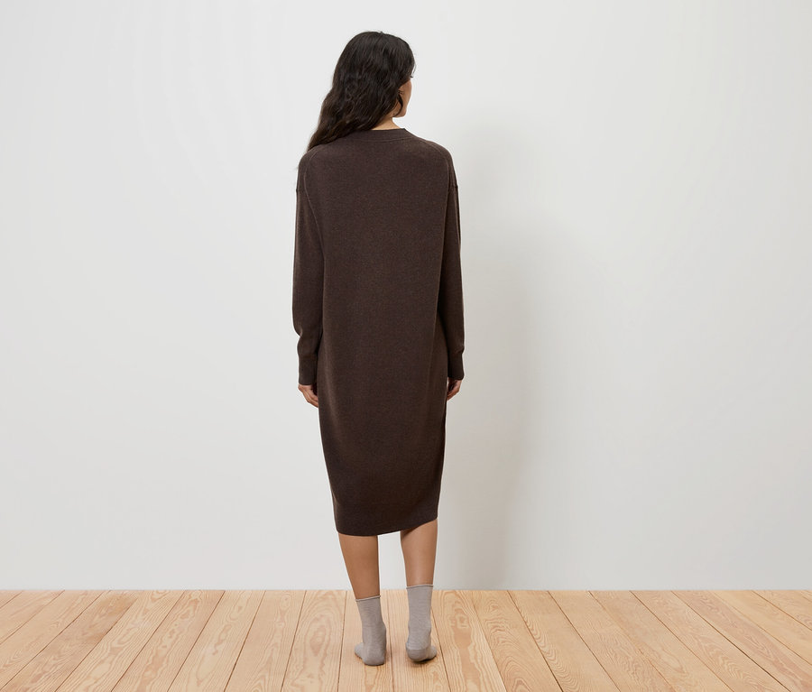 Une femme, vue de dos, porte une robe marron et des chaussettes grises.