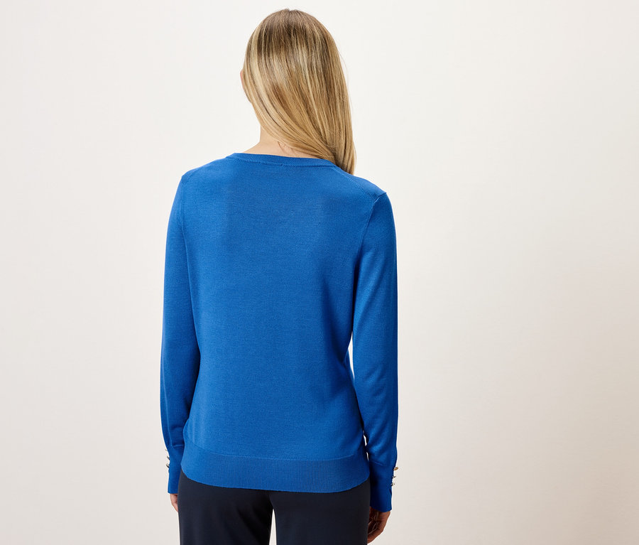 Femme blonde vue de dos portant un pull bleu.