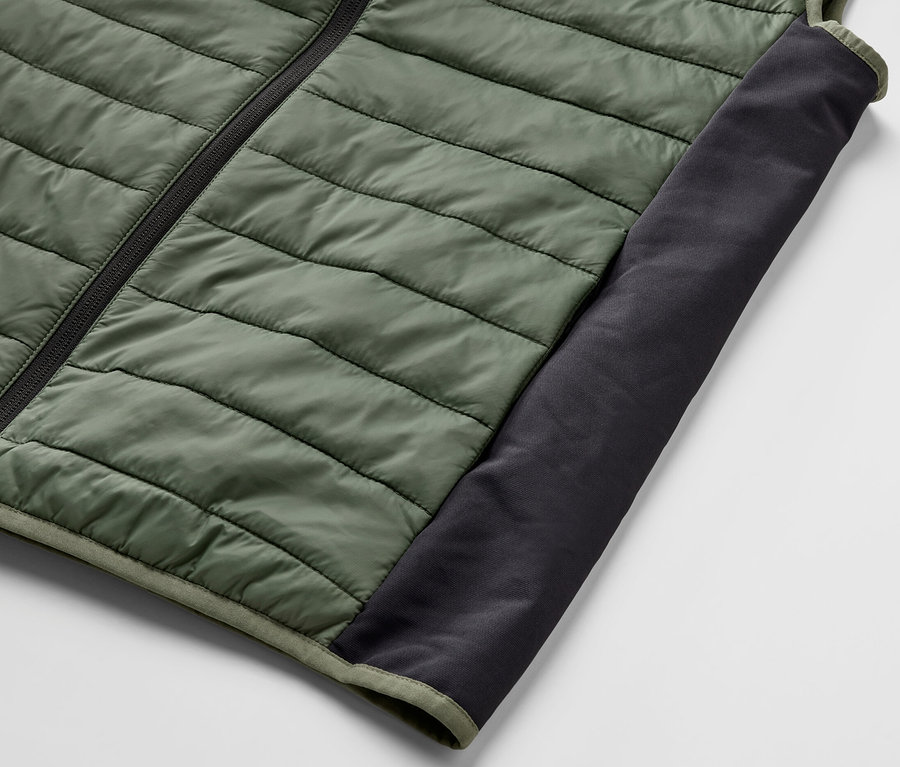 Détail d'un gilet matelassé vert « pack light » avec fermeture éclair noire et empiècement.