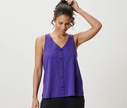 Une femme ajuste ses cheveux et porte un haut violet en mélange de modal.