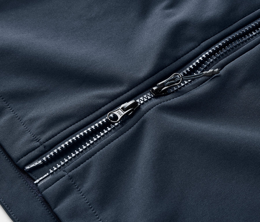 Gros plan sur un manteau en softshell bleu marine avec une fermeture éclair argentée.