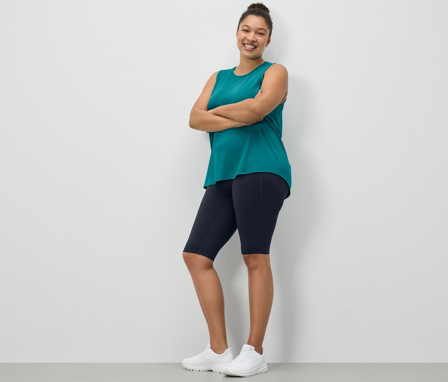 Femme posant en cycliste de sport bleu foncé et débardeur de sport turquoise d'un ensemble de 2.