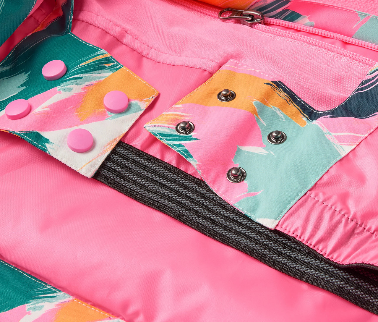 Détail d'une veste avec doublure rose, motifs colorés et boutons-pression.