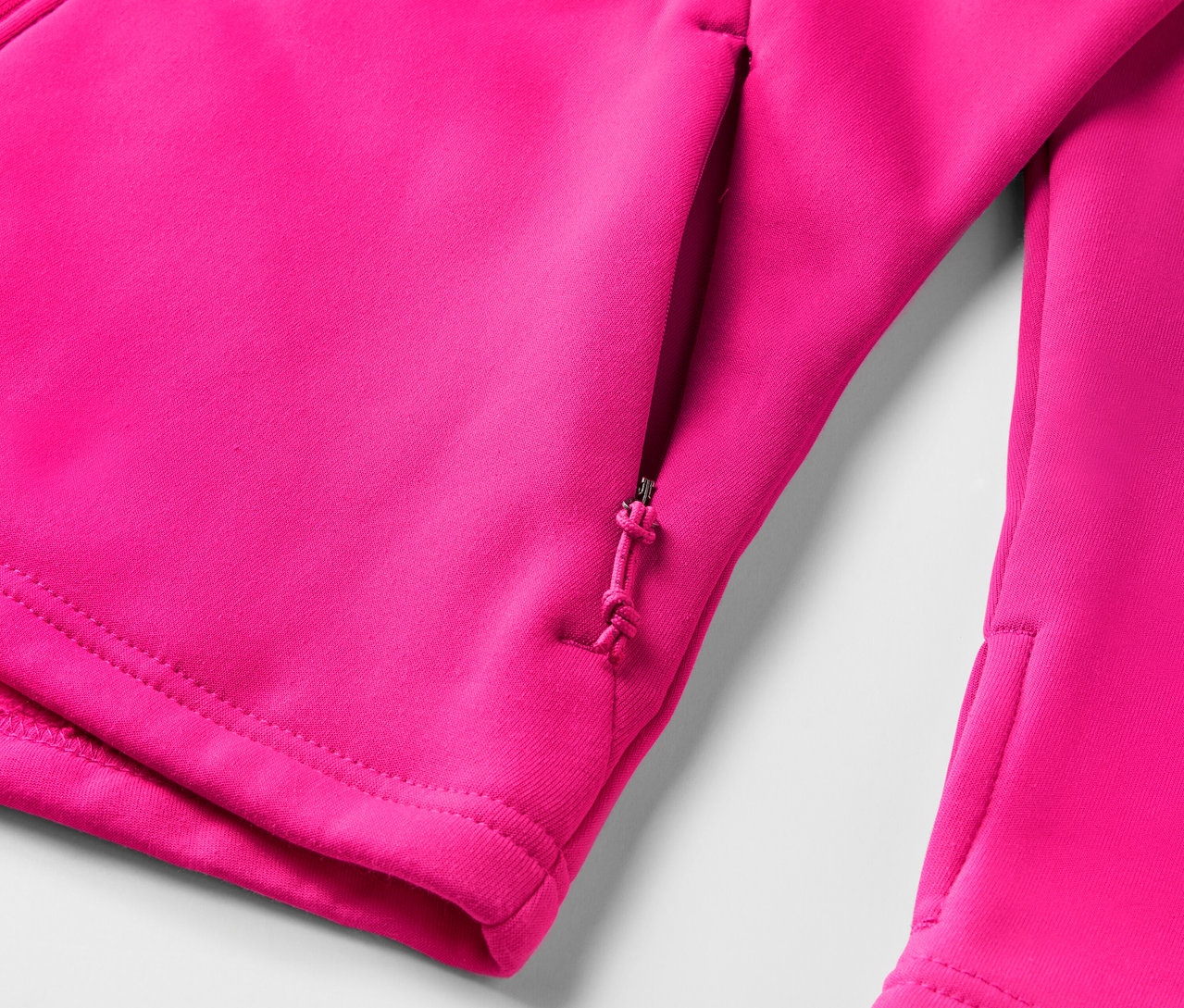 Détail d'un sweat à capuche rose avec une poche zippée.