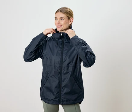 Femme ajustant une veste à capuche bleu marine et souriant.