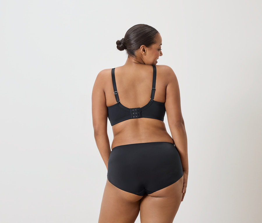 Vue arrière d'une femme portant un chignon, un soutien-gorge noir et une culotte noire.