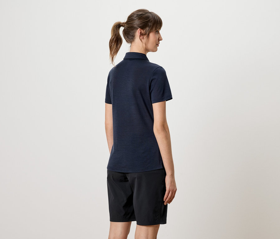 Femme vue de dos, portant un polo foncé et un short noir.