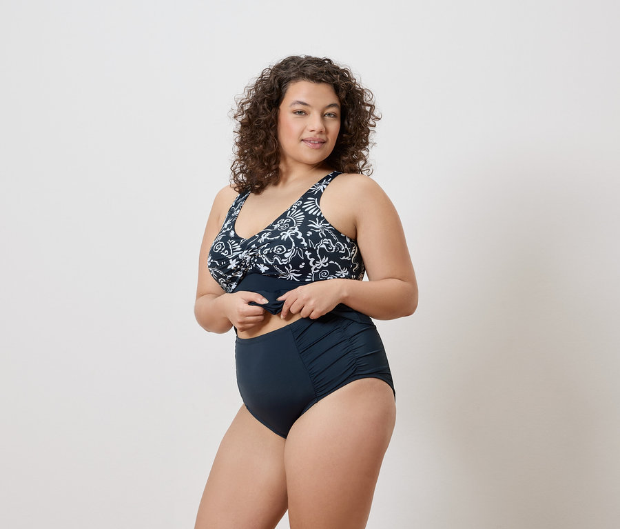 Femme portant un maillot de bain bleu marine à motif floral.