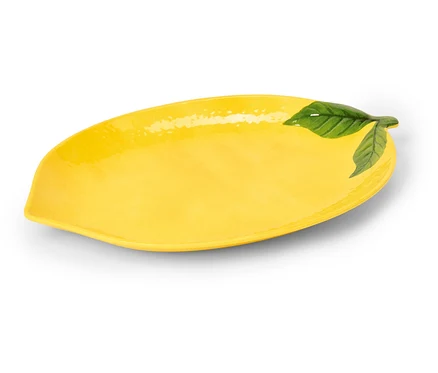 Plat oblong en céramique jaune en forme de citron avec des feuilles vertes à une extrémité.