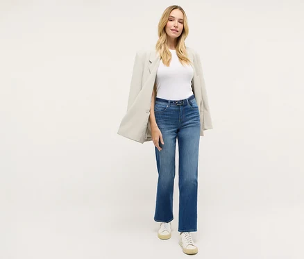 Femme portant un jean droit « Lara City » Angels, un t-shirt blanc, un blazer et des baskets.